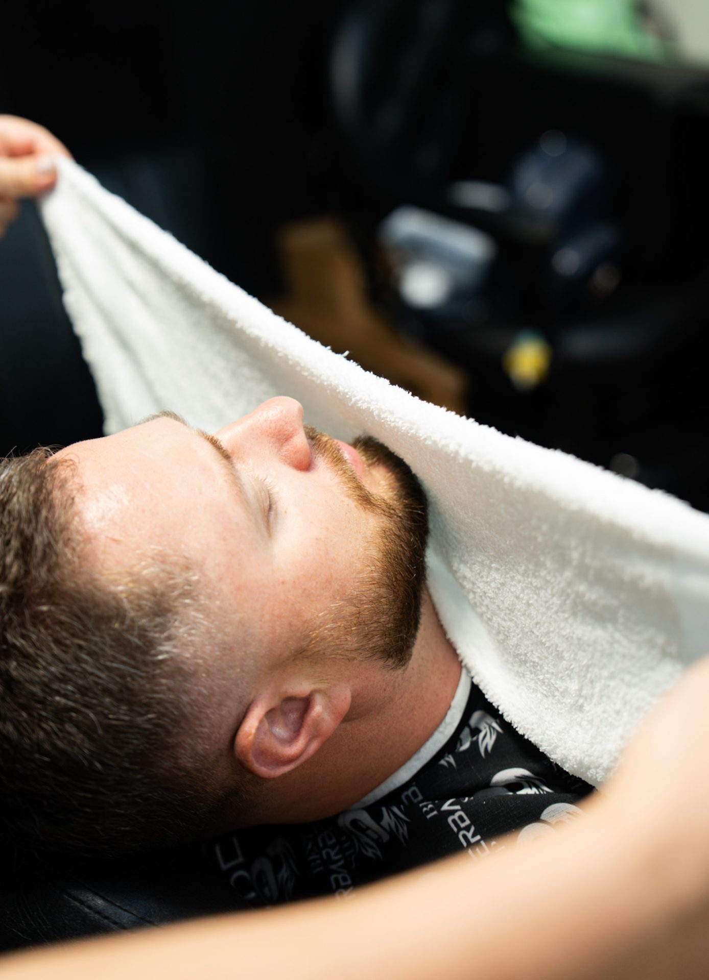 Barber laying a hot towel over a client’s face