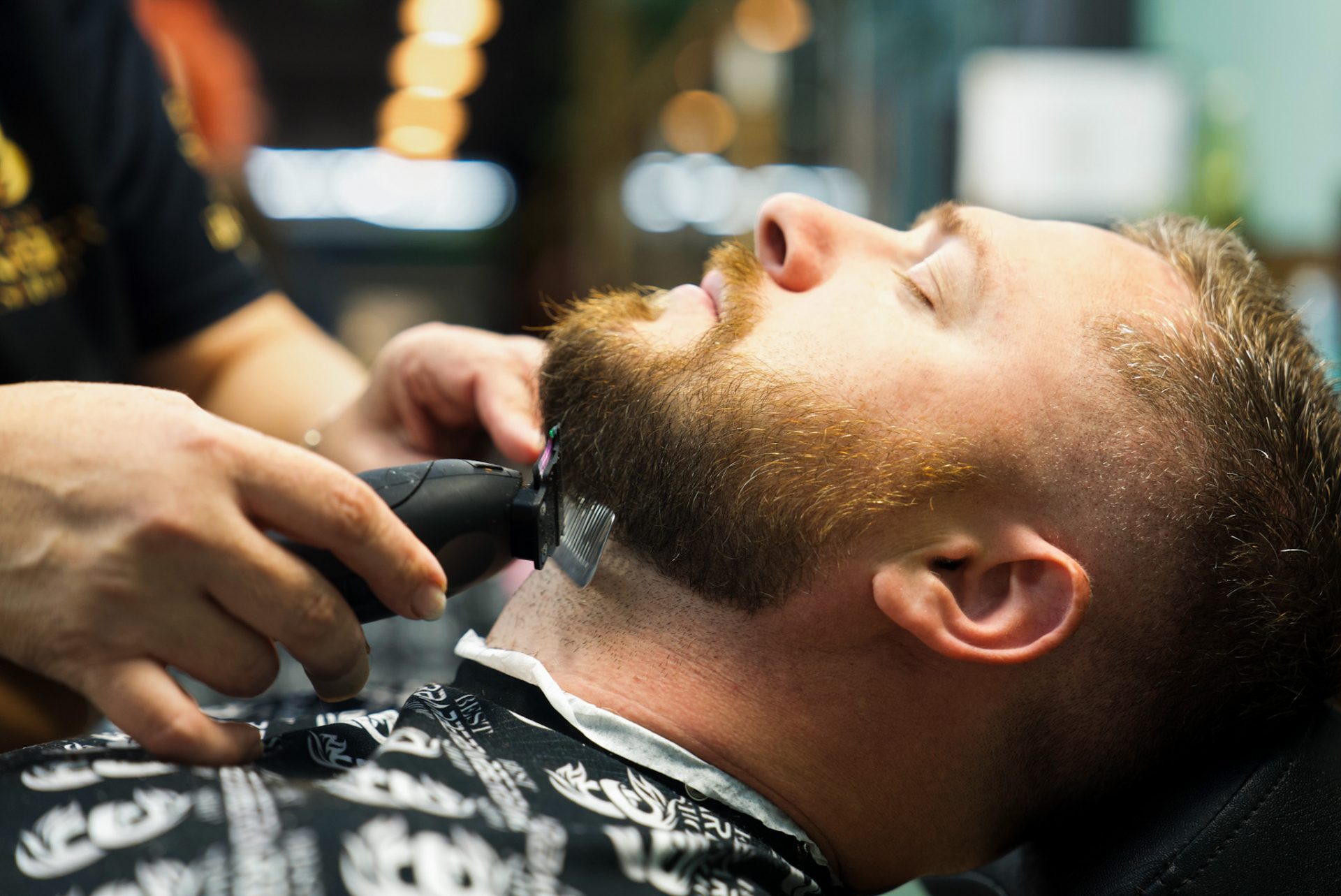Barber trimming a client’s beard with clippers